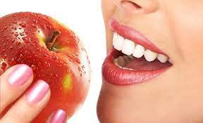 ilustracija osmeha i jabuke koju devojka drži u ruci blizu usana